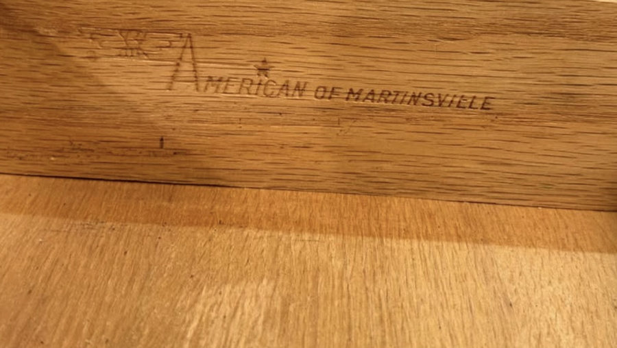 The words American of Martinsville stamped into oak, with a small star and a winged emblem over the letter A