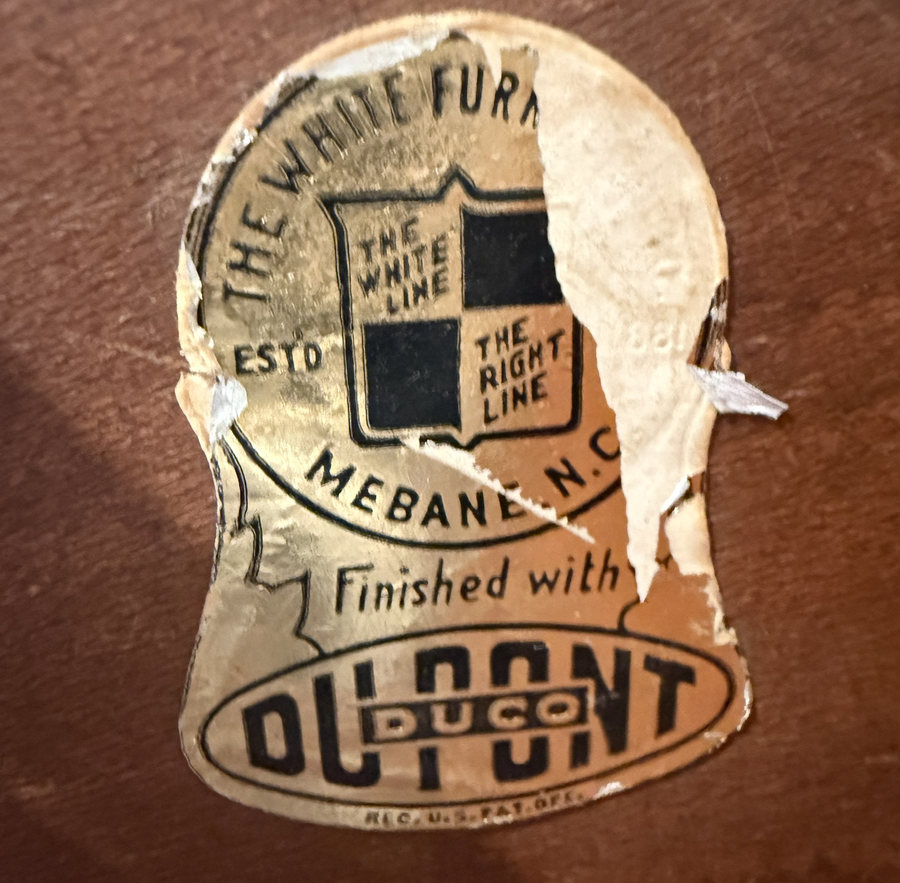 A torn gold paper label reading The White Furniture Co., Mebane N.C., The White Line The Right Line, Finished with DuPont Duco